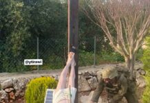 Soldado israelense fardado usando uma marreta para destruir a cabeça de uma estátua de Jesus Cristo caída no chão em um jardim no sul do Líbano.