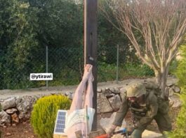 Soldado israelense fardado usando uma marreta para destruir a cabeça de uma estátua de Jesus Cristo caída no chão em um jardim no sul do Líbano.