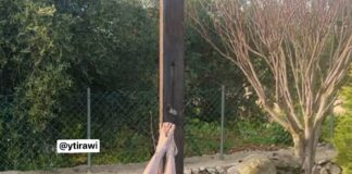 Soldado israelense fardado usando uma marreta para destruir a cabeça de uma estátua de Jesus Cristo caída no chão em um jardim no sul do Líbano.